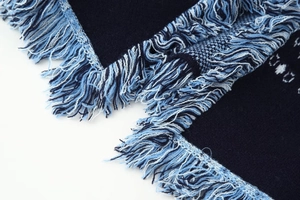 Close-up of knit cardigan with navy blue fringe trim and soft jacquard fabric texture