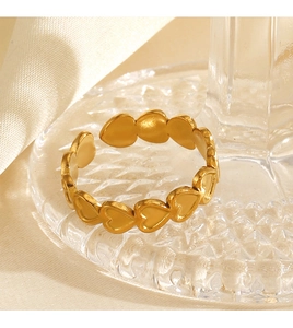 Macro view of adjustable 18K gold plated heart ring on textured glass and white silk