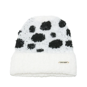 Detailed view of fluffy cow print knit beanie featuring a gold metal brand logo tag