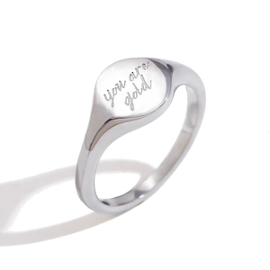 Polished silver stainless steel signet ring with you are gold engraving on white surface