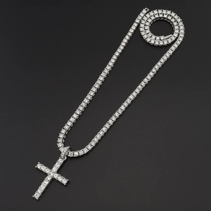 Close-up of silver tennis chain necklace with a large iced-out cross pendant on black background