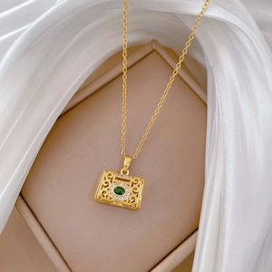 Vintage gold titanium steel necklace with green gem pendant on white silk fabric