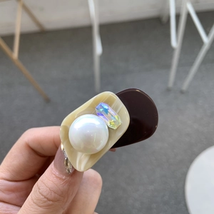 Close-up of acetic acid hair clip with cream and coffee tones, pearls and crystals