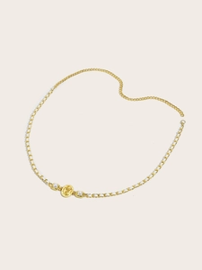 Detail of gold chain belt with white ribbon and pearl accents in a heart shape layout