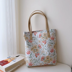 Close-up of floral cotton tote bag featuring leather handles and secure metal rivets