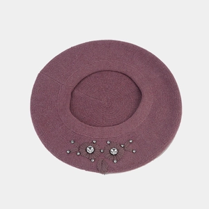 Détail du béret en maille violet foncé avec fleurs brodées et accents de strass