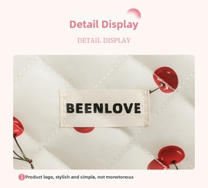 Detailed close-up of quilted floral cosmetic bag with cherry pattern and brand label