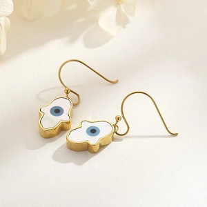 Macro detail of Hamsa Hand and Evil Eye gold earrings with mother of pearl inlay