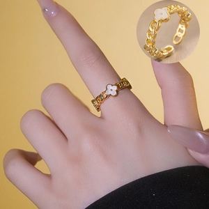 Golden open ring with shell clover flower pendant shown on model with macro detail