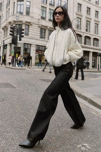 Street-Style-Ansicht einer weißen strukturierten Zip-Jacke mit schwarzer Wide-Leg-Jeans