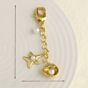 Détail macro d'un pendentif étoile de mer et coquillage doré 15x82mm avec perles