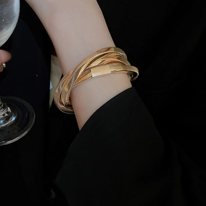 Detail view of a multi-layer twisted gold snake chain bracelet worn on a female wrist