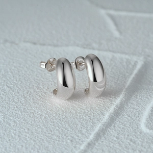 Macro shot of S925 sterling silver C-shaped earring showing hallmark and mirror finish