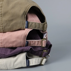 Detail of multi-color cotton baseball caps with adjustable bronze metal buckle and woven label