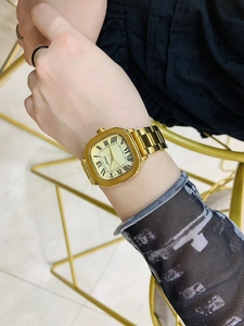 Close-up of vintage rectangular gold watch with roman numerals on a woman's wrist