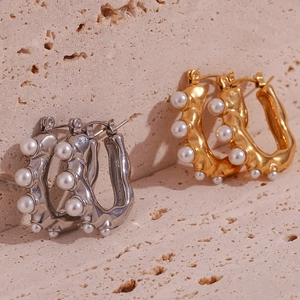 Macro view of U-shaped gold and silver earrings with pearl accents and lava texture