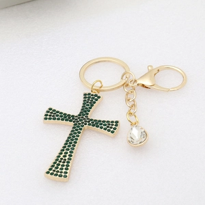 Detail of gold keychain with green rhinestone cross and clear teardrop crystal pendant