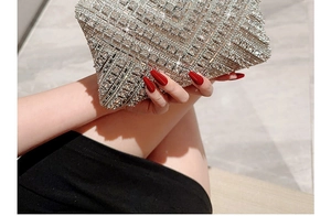 Close-up of a luxury silver rhinestone clutch bag held by a model with red nails