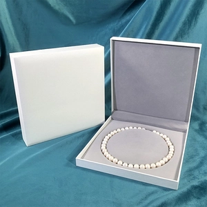 Detailed view of an elegant white leather jewelry box with grey velvet interior for necklaces