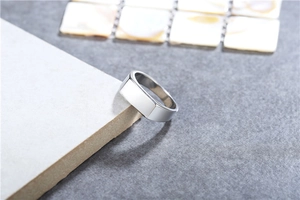 Detailed view of wide flat-top silver titanium steel ring on a textured stone surface