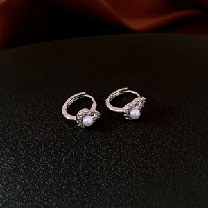Close-up of silver hollow gourd earrings with white pearl and sparkling zircon details