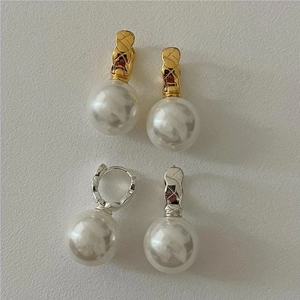 Detail of elegant gold and silver earrings with quilted pattern and large pearls