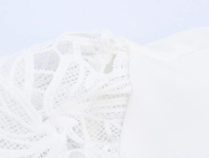 Close-up of white lace embroidery details and premium stitched fabric on blouse