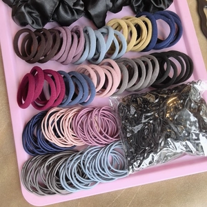 Detail view of assorted colorful elastic hair ties and black scrunchies in a tray