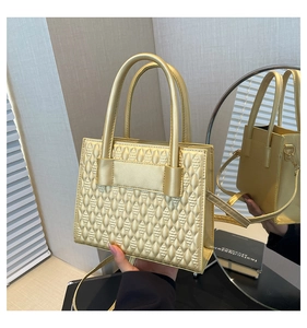 Détail d'un sac à main doré mat avec motif géométrique et bandoulière amovible