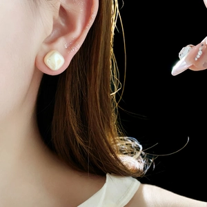 Detail view of square pearl stud earring in 14K gold plating worn on ear