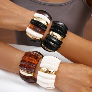 Close-up of stacked oversized acrylic bangles in tortoiseshell and ivory on a model