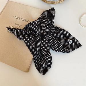 Close-up of fabric polka dot hair scrunchie with metallic logo on a vintage background