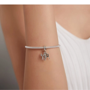Detailed close-up of a silver charm bracelet with hairdryer, comb, and scissor pendants