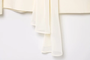 Détail d'un blazer crème avec tissu tissé et écharpe en mousseline de soie élégante