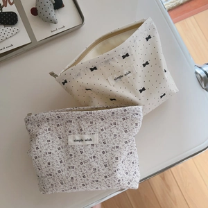 Close-up of small floral and polka dot fabric makeup bags with zipper and logo labels