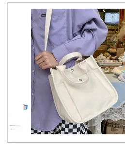 Close-up of cream canvas tote bag showing stitching details and metal snap button