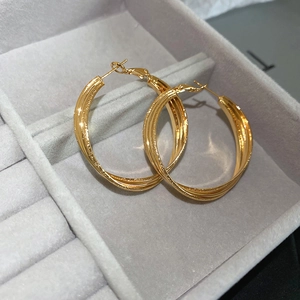 Vue macro de boucles d'oreilles créoles torsadées dorées 18k dans un écrin en velours gris
