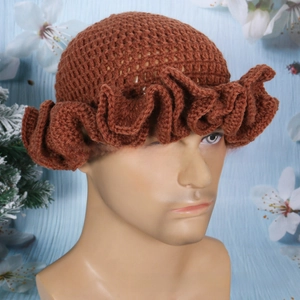 Close-up of handmade crochet ruffle beanie in brownish red with thick wool knit texture