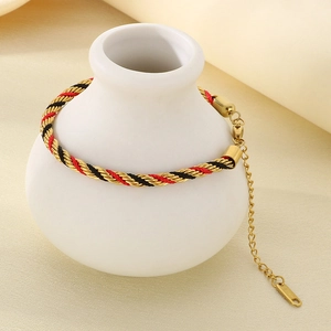 Detail of a handmade braided bracelet in gold, red, and black with lobster clasp