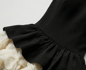 Detail of elegant black dress showing contrast white 3D petal ruffles and fishtail hemline