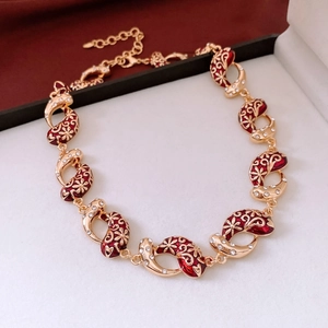 Macro detail of gold flower necklace with red enamel and clear zircon stones