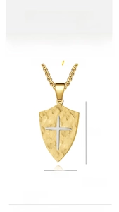 Close-up of titanium steel shield pendant with gold hammer texture and silver cross