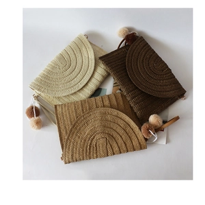 Straw clutch bags with pompoms in beige, khaki, and brown on a minimalist white background