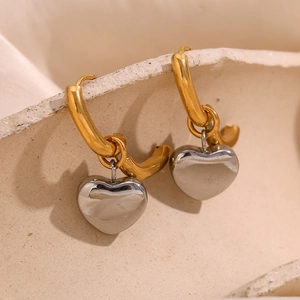 Detail shot of heart-shaped pendant earrings with gold and silver two-tone metal finish