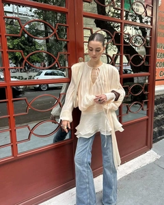 Detail of beige pleated puff sleeve top with tiered hem and drawstring accents