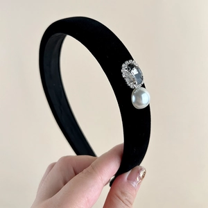 Detail of velvet headband featuring a large dark rhinestone and a white hanging pearl charm