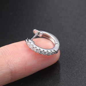 Macro shot of silver huggie earring with micro-pave zircons held on a fingertip