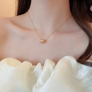 Close-up of 18k gold plated flower lock necklace worn on collarbone with white top