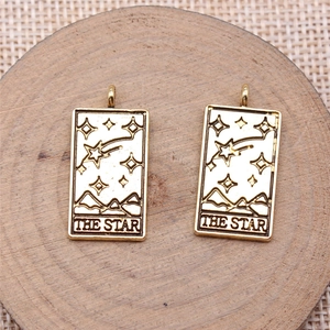 Detailed view of two gold The Star tarot card pendants on a wooden display base