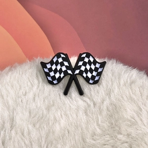 Detail shot of vintage racing flag enamel brooch on soft white plush background